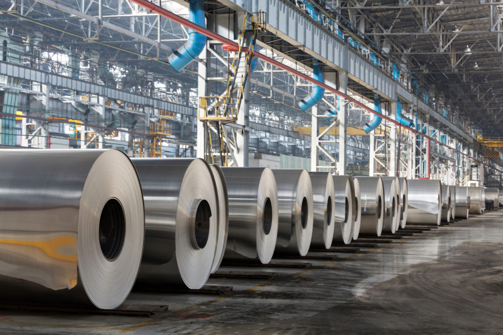 Row of rolls of aluminum lie in production shop of plant.