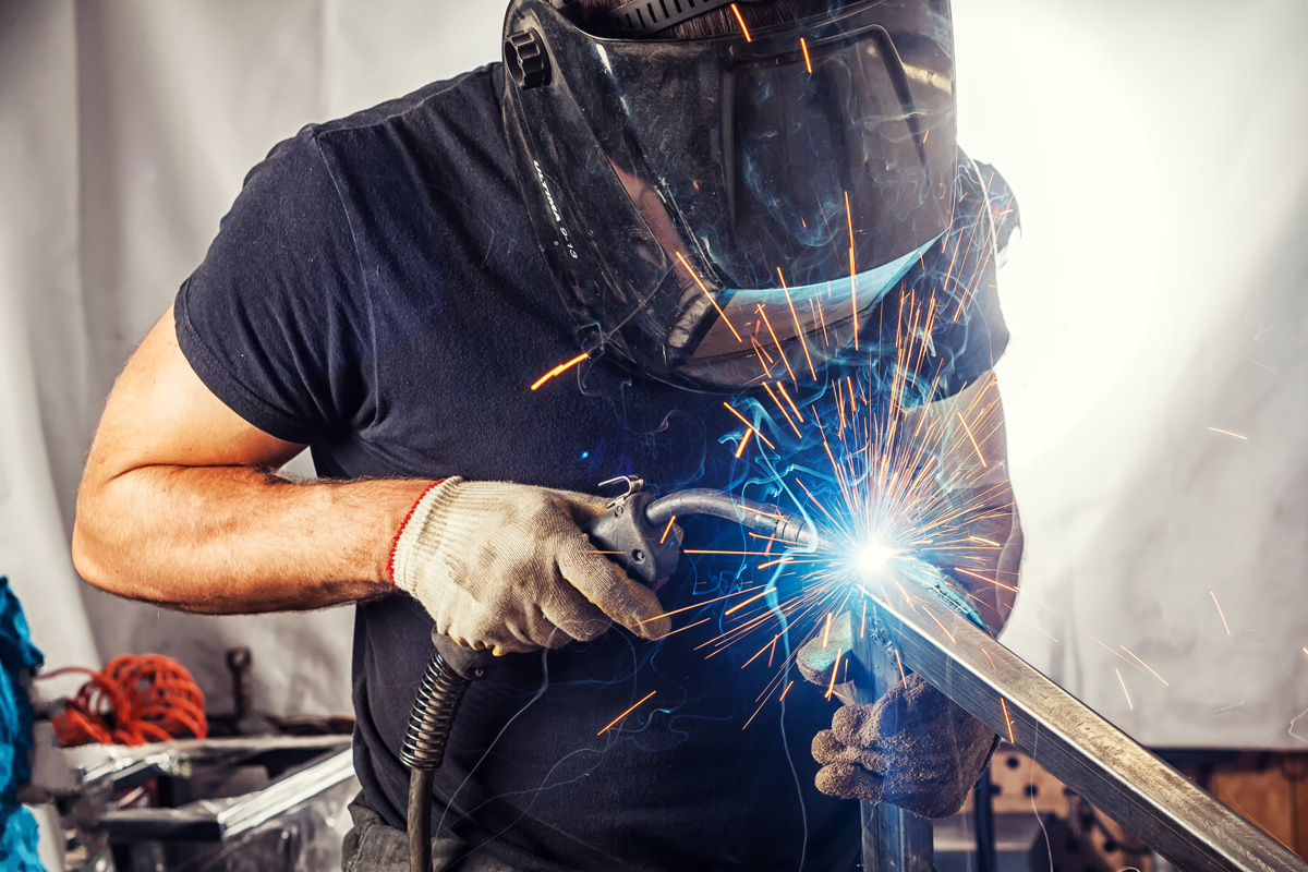 A person in a protective mask performing aluminum fabrication in El Paso.